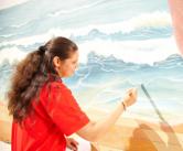 Eine junge Malerin malt ein Wandbild.